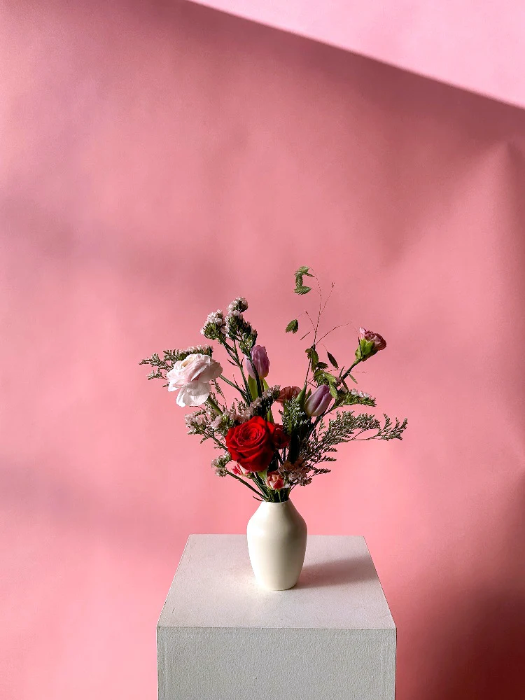 Vancouver Florist - Vancouver Flower Delivery - Valentine's Flowers, White vase with flowers on a gray pedestal against a pink background